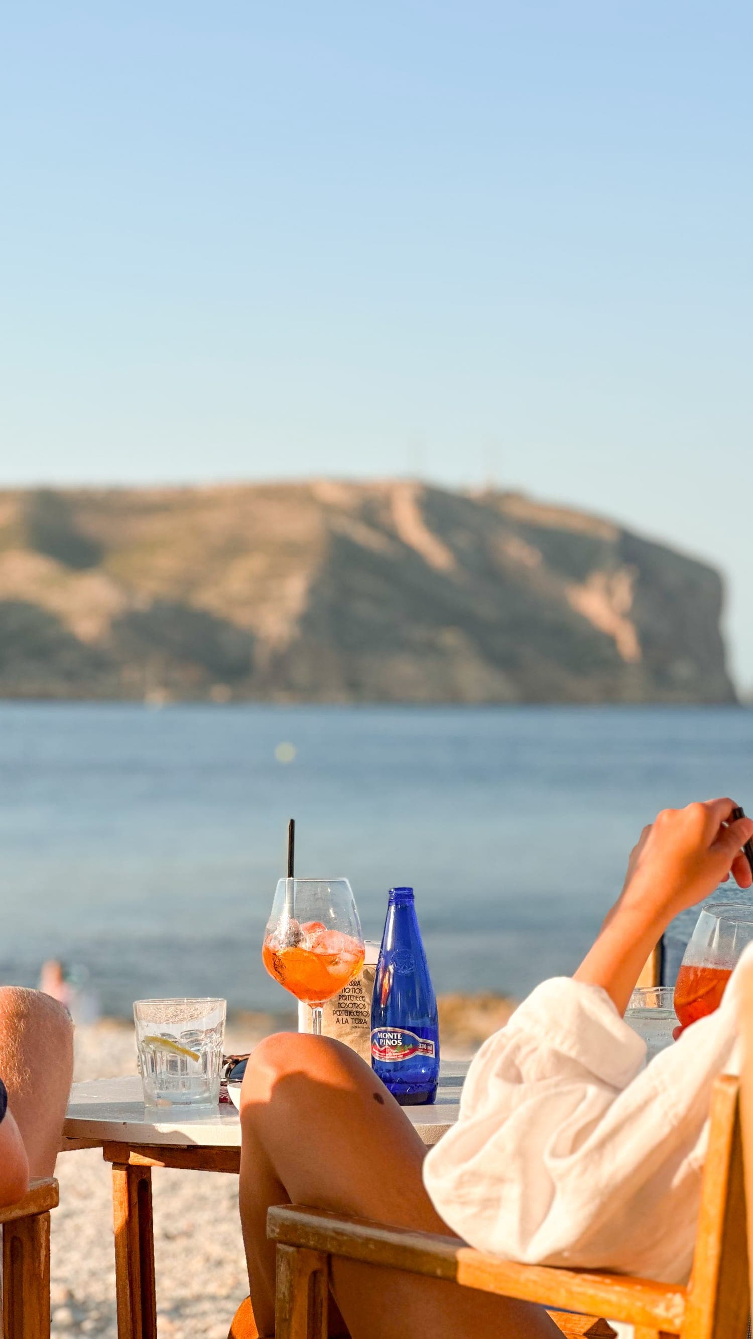 Casal num bar à beira-mar do Mediterrâneo com Aperol Spritz no entardecer