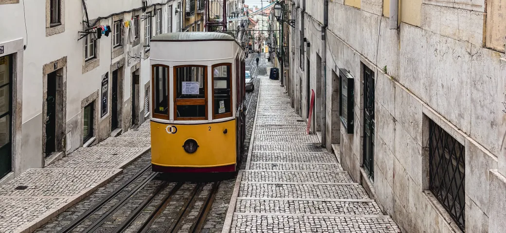 O elevador da Bica, bonde amarelo numa ladeira de pedra portuguesa em Lisboa